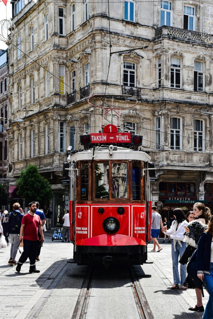 Iconic vintage red tram in bustling Taksim Square, Istanbul, a symbol of urban transport and tourism.
